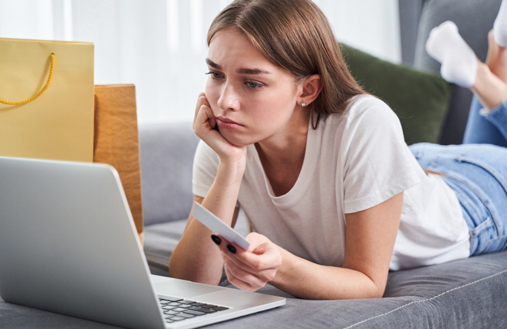 Sad women looking at laptop with card